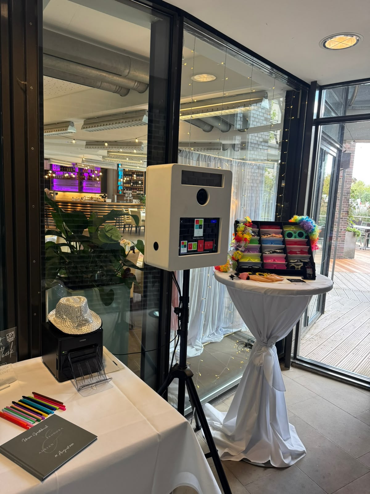 Weiße GrinseLinse Fotobox mit Requisiten in einer modernen Eventlocation